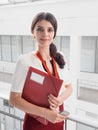 Beautiful Smiling Businesswoman Standing Against White Offices Background. Portrait of Business Woman With a Folder in Her Hands Royalty Free Stock Photo