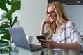 beautiful smiling businesswoman using laptop and smartphone while working