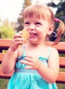 Beautiful smiling cheerful girl eats ice cream on the bench in t Royalty Free Stock Photo