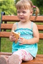 Beautiful smiling cheerful girl eats ice cream on the bench in t Royalty Free Stock Photo