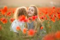 Beautiful smiling child girl with mother are having fun in field of red poppy flowers over sunset lights Royalty Free Stock Photo