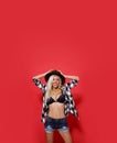 Beautiful smiling crazy young woman with blonde hair, posing sexy with bare abdomen, in underwear, over red background.