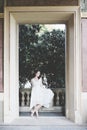 Beautiful curly hair girl in a light blue simple dress in a pavilion in a garden