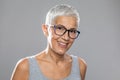 Smiling senior woman with short white hair and glasses posing in front of gray background Royalty Free Stock Photo