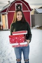 Beautiful smiling Diverse teen girl delivery a Christmas present to a friend. Holding a stack of wrapped presents and walking th Royalty Free Stock Photo