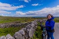 Beautiful and smiling female cyclist pausing on a road next to a stone fence on the Inis Oirr island Royalty Free Stock Photo