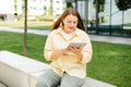 Beautiful smiling female student using tablet outdoors. Happy cheerful young woman siting on the bench on city street Royalty Free Stock Photo