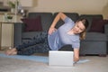 Beautiful smiling girl doing yoga pose at home. Woman training at home, doing plank and watching videos on laptop, training in Royalty Free Stock Photo