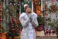 Beautiful smiling girl drinking tea, coffee or other hot drink in winter on the background of a christmas house Royalty Free Stock Photo