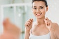 beautiful smiling girl holding dental floss and looking at mirror Royalty Free Stock Photo