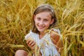 A beautiful smiling girl with ice cream in her hands is sitting and eating at a picnic in a wheat field. Summer mood Royalty Free Stock Photo