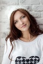 Beautiful smiling girl sitting near the window in warm white cap