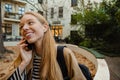 Beautiful smiling girl talking on mobile phone while sitting in yard Royalty Free Stock Photo