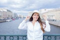 A beautiful and smiling girl in a white hat with wide brim is standing on the bridge and talking on the phone against the backgrou Royalty Free Stock Photo