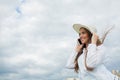 A beautiful and smiling girl in a white hat with wide brim is standing on the bridge and talking on the phone against the backgrou Royalty Free Stock Photo