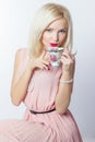 Beautiful smiling happy elegant girl with red lipstick in a pink dress in retro style drinks tea coffee from a small mugs