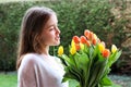 Beautiful smiling happy tween girl holding big bouquet of bright yellow and orange tulips talking to them Royalty Free Stock Photo