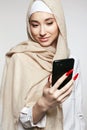 beautiful smiling islamic young woman with smartphone. Happy girl in hijab looking at the screen