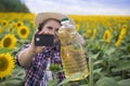 Beautiful smiling joyful middle-aged farmer woman  in a straw hat and a plaid shirt stands in defocus blur a field of  golden sunf Royalty Free Stock Photo