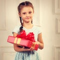 Beautiful smiling kid girl holding present box with red ribbon b Royalty Free Stock Photo