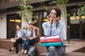 Beautiful smiling lady sitting on bench with colorful folders on knees and joyfully looking in camera while spending Royalty Free Stock Photo