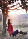 Beautiful smiling lady sitting under a tree with sunset on background Royalty Free Stock Photo