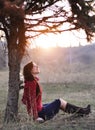 Beautiful smiling lady sitting under a tree with sunset on background Royalty Free Stock Photo