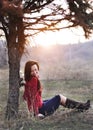 Beautiful smiling lady sitting under a tree with sunset on background Royalty Free Stock Photo