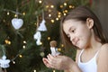 Beautiful smiling little girl decorating Christmas tree and holding angel doll in her hands Royalty Free Stock Photo