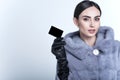 Beautiful smiling model wearing blue mink fur coat and long leather gloves holding black blank business card Royalty Free Stock Photo