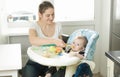 Beautiful smiling mother feeding her baby on kitchen Royalty Free Stock Photo