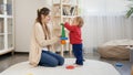 Beautiful smiling mother helping her little baby son assembling toy tower. Baby development, child playing games, education and Royalty Free Stock Photo