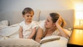 Beautiful smiling young mother with her toddler son lying in bed at night Royalty Free Stock Photo