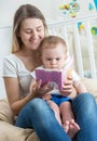 Beautiful smiling mother reading story to her 9 months old baby Royalty Free Stock Photo