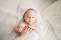 Beautiful smiling newborn baby boy covered with white bamboo towel with fun ears. lies on a white knit, wool plaid bright interior Royalty Free Stock Photo