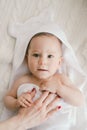 Beautiful smiling newborn baby boy covered with white bamboo towel with fun ears. lies on a white knit, wool plaid bright interior Royalty Free Stock Photo