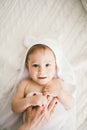 Beautiful smiling newborn baby boy covered with white bamboo towel with fun ears. lies on a white knit, wool plaid bright interior Royalty Free Stock Photo