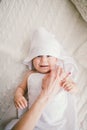 Beautiful smiling newborn baby boy covered with white bamboo towel with fun ears. lies on a white knit, wool plaid bright interior Royalty Free Stock Photo