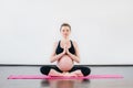 Beautiful smiling pregnant girl doing yoga exercises in fitness studio.