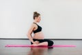 Beautiful smiling pregnant girl doing yoga exercises in fitness studio. White background.