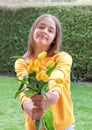 Beautiful smiling preteen girl giving bouquet of spring yellow tulips looking at camera.