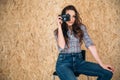 A beautiful smiling pretty girl photographer sits on a chair in her studio, adjusts her dark long hair, and holds the Royalty Free Stock Photo