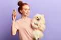 Beautiful smiling red-haired girl holding adorable pet and bone