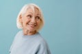 Beautiful smiling senior woman in blue pullover looking rightward