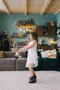 A beautiful smiling seven-year-old girl dances with a stuffed toy in the living room decorated for Christmas, waiting for the Royalty Free Stock Photo