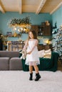 A beautiful smiling seven-year-old girl dances with a stuffed toy in the living room decorated for Christmas, waiting for the Royalty Free Stock Photo