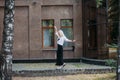 woman with long blond hair, in a black long dress and a white shirt, walks along the city street Royalty Free Stock Photo