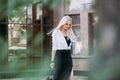 woman with long blond hair, in a black long dress and a white shirt, walks along the city street Royalty Free Stock Photo