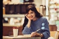 Beautiful smiling student woman reading a book in the cafe with warm cozy interior and drinking coffee Royalty Free Stock Photo