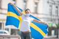 Beautiful smiling Swedish girl holds a flag while wearing a protective face mask outdoors Royalty Free Stock Photo